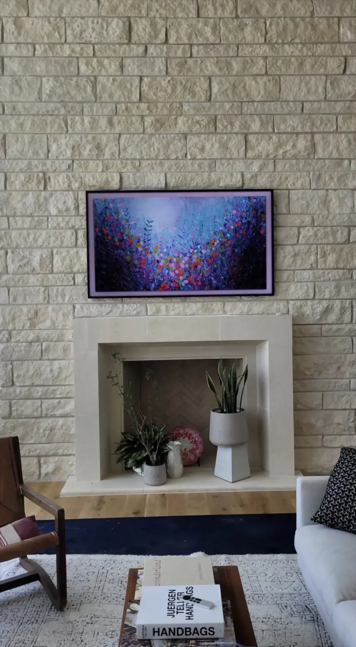 Samsung Frame TV displaying floral art on a limestone brick wall above a cast stone fireplace
